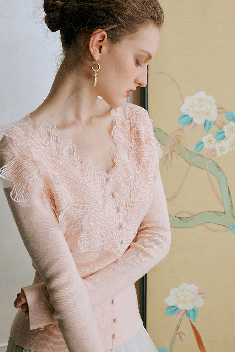Top de punto con detalles de encaje y plumas
