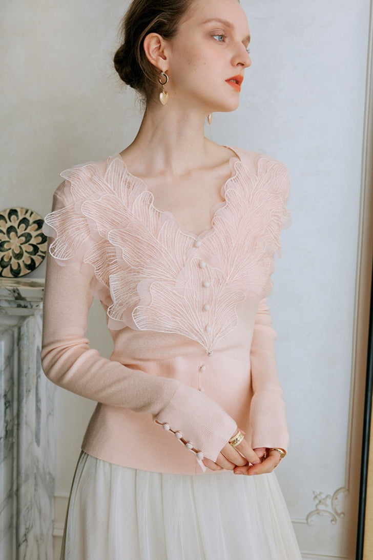 Top de punto con detalles de encaje y plumas